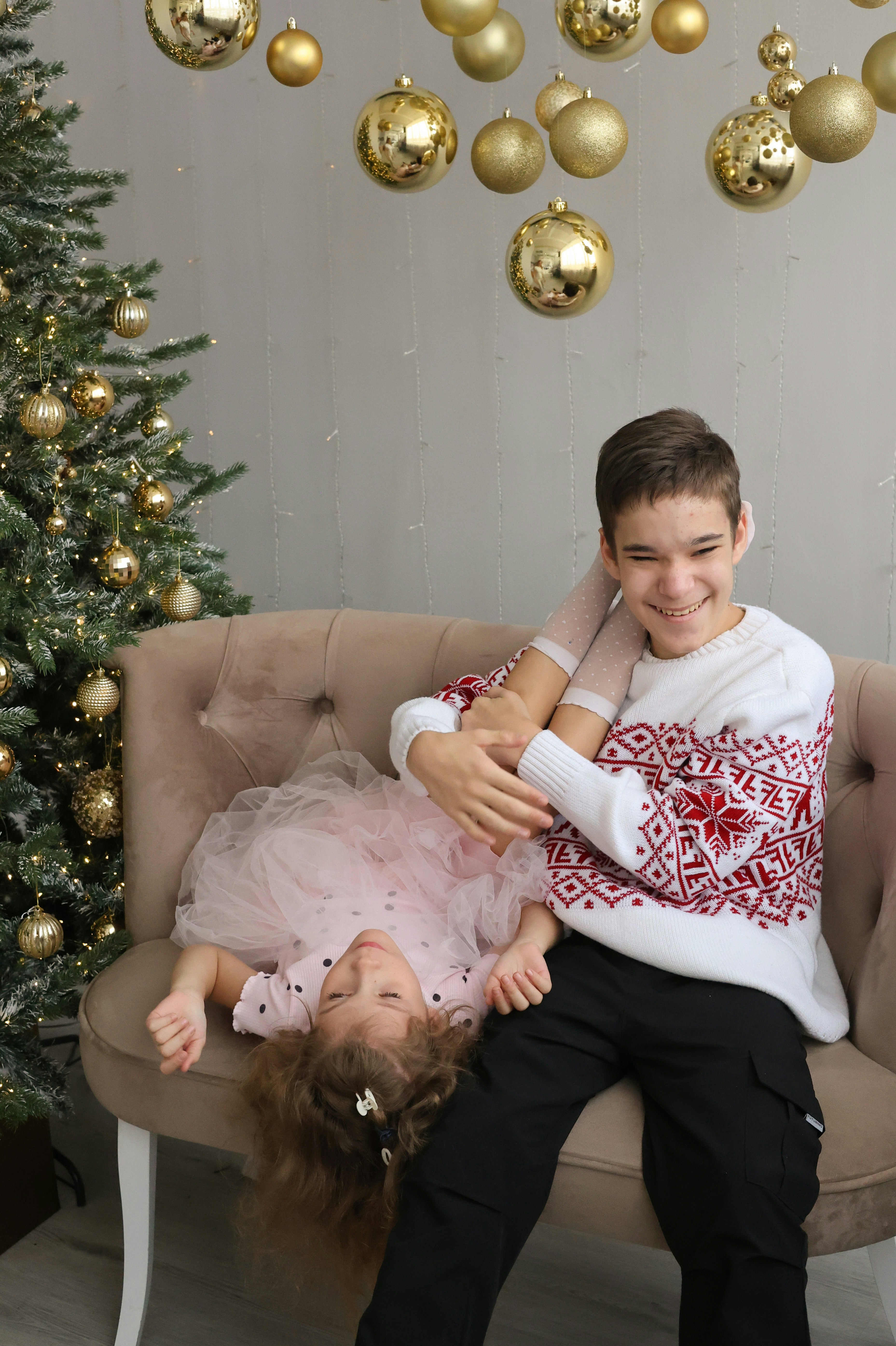 Ein Junge und ein Mädchen sitzen auf einer Couch vor einem Weihnachtsbaum