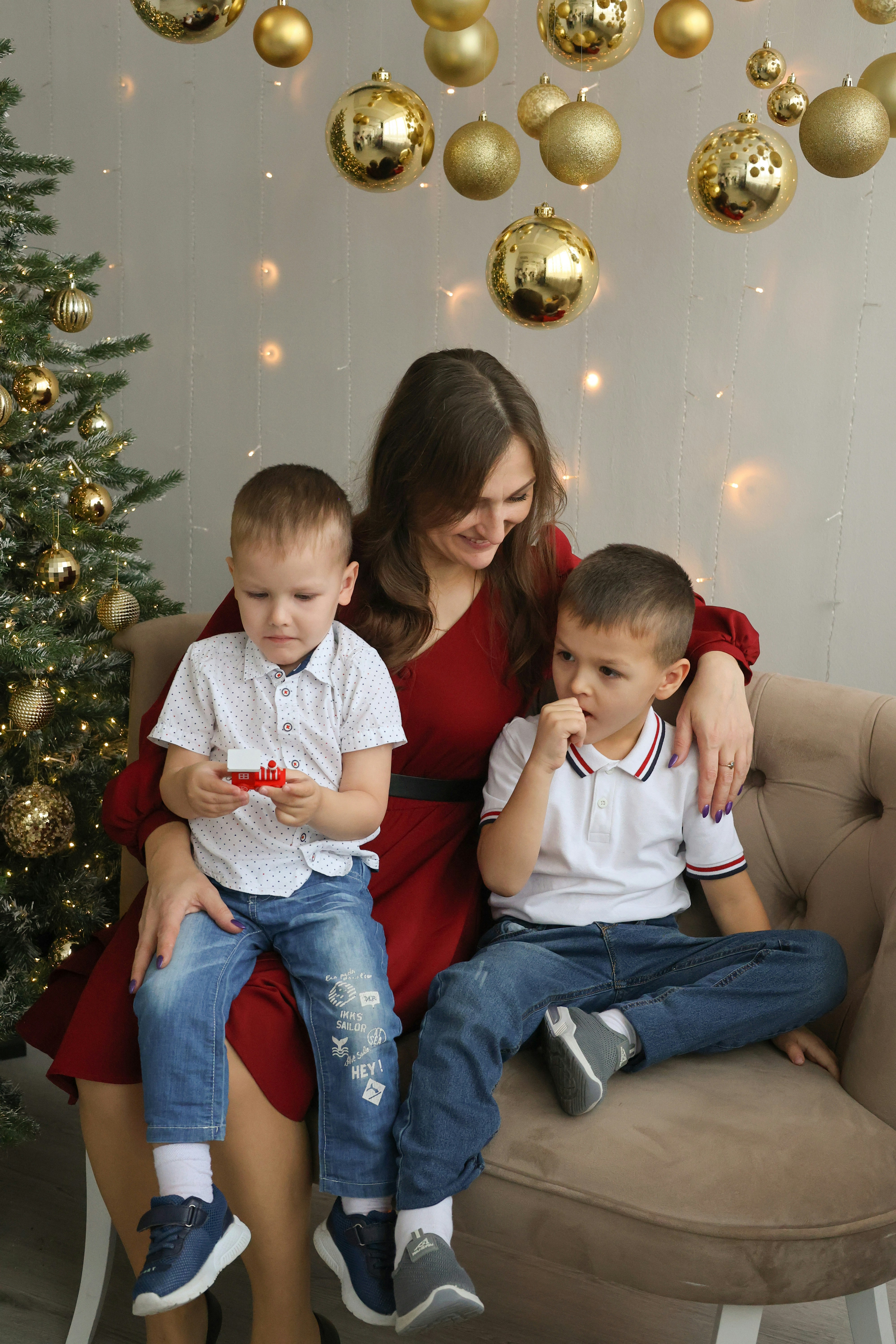 A woman and two children sitting on a couch in front of a christmas tree