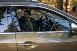 A man sitting in a car holding a steering wheel