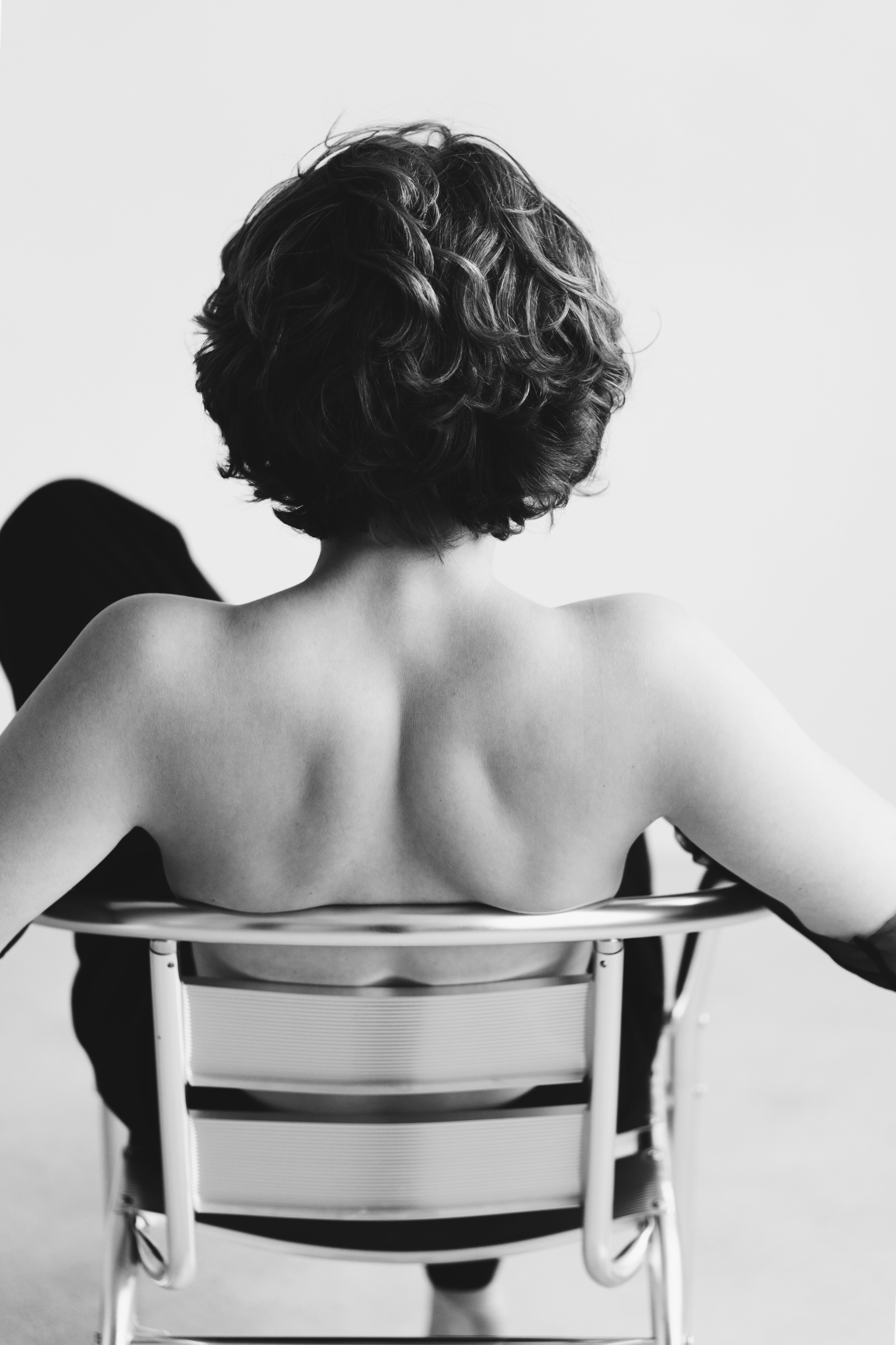 Une femme assise sur une chaise, dos à la caméra