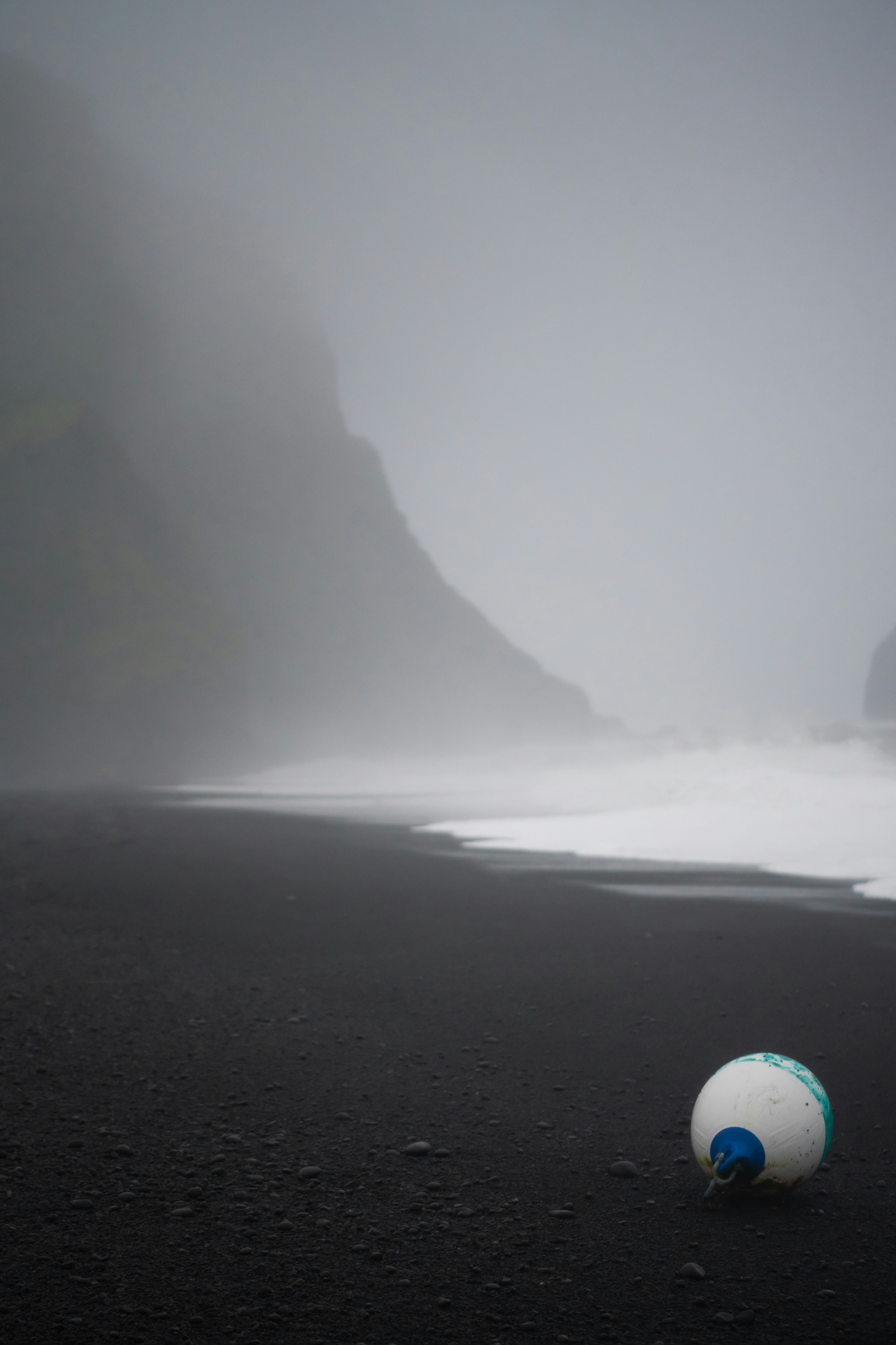 A ball sitting on the beach in the fog