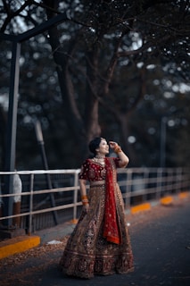 A woman in a red and gold dress standing on a bridge