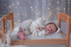 A baby laying in a crib with a teddy bear