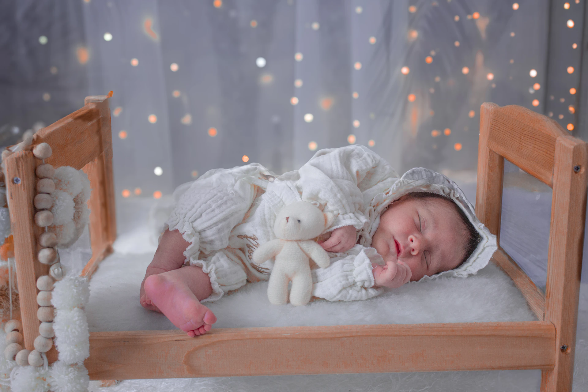 A baby laying in a crib with a teddy bear