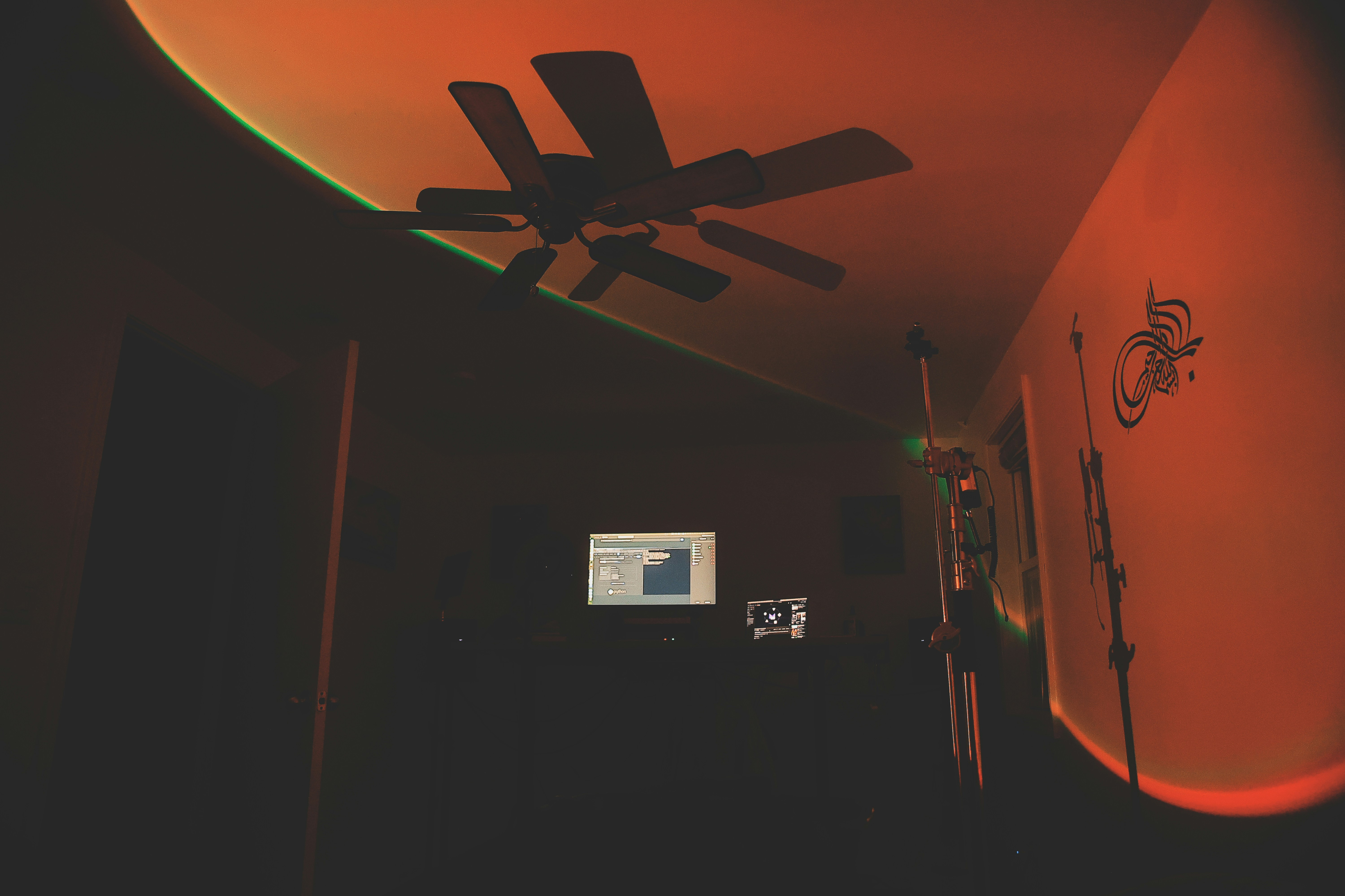 A room with a ceiling fan and a television