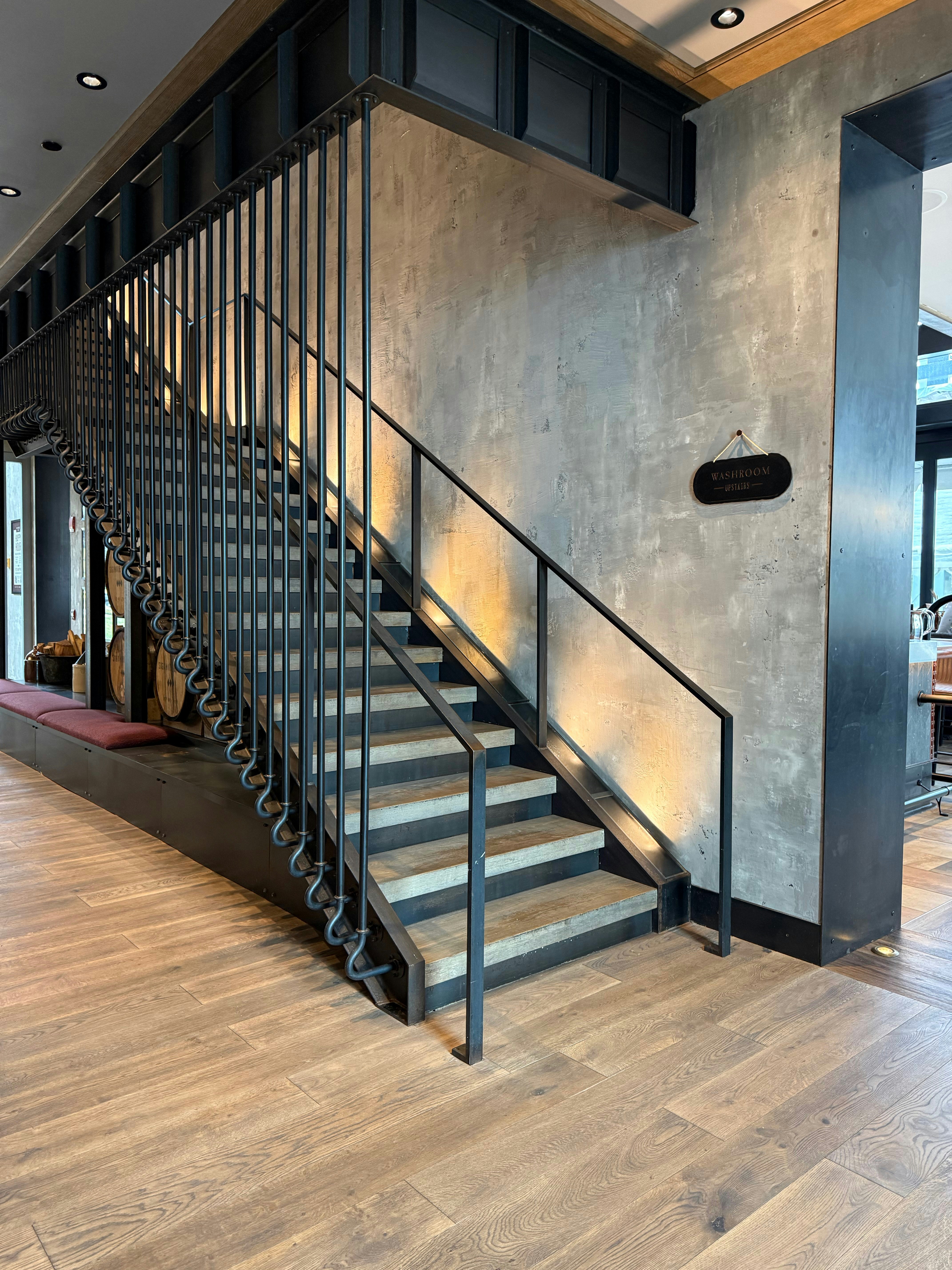 Modern industrial steel staircase with custom fabricated railings in a commercial interior, dark polished metal finish