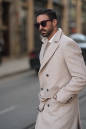A man in a trench coat is standing on the street