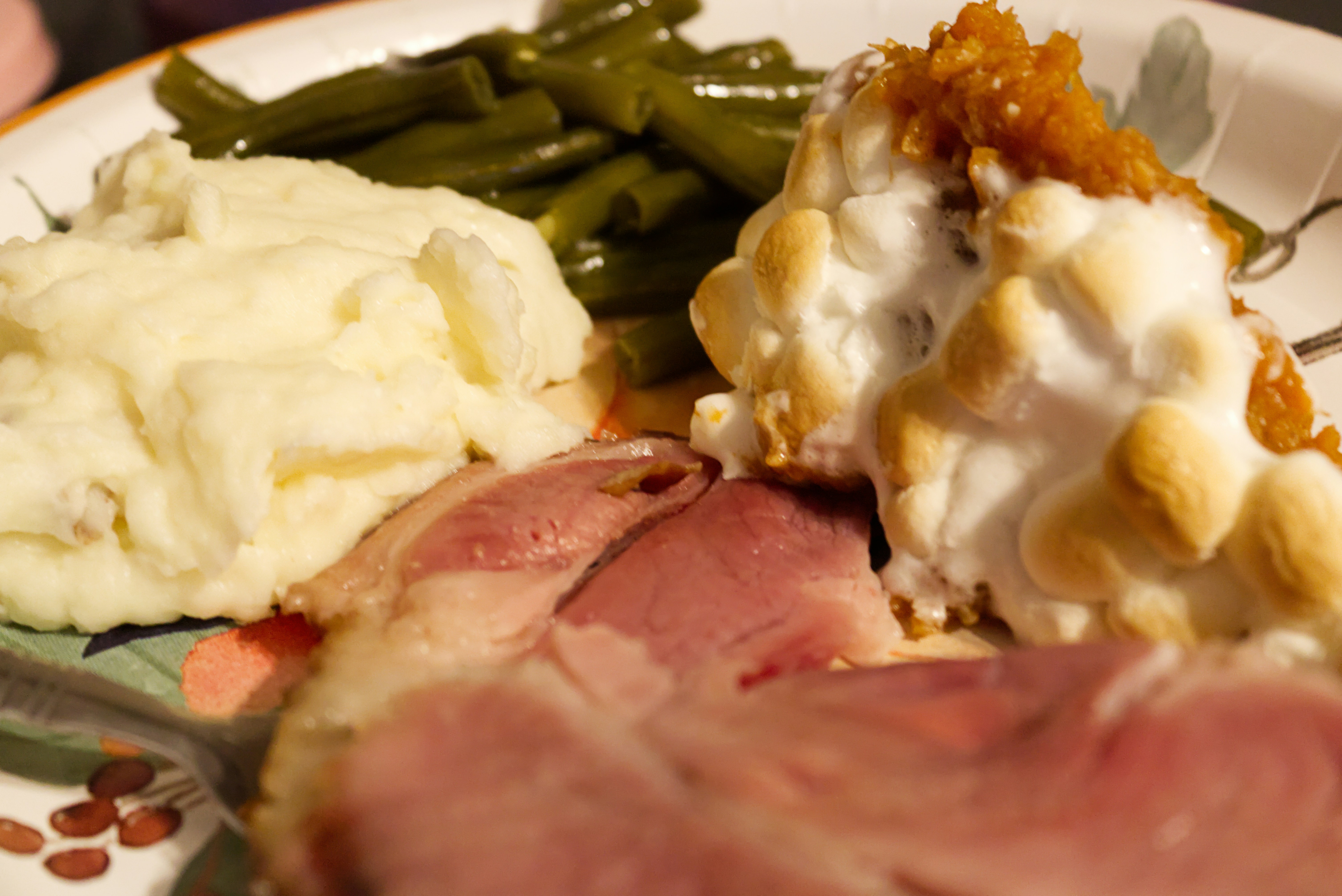 A white plate topped with meat, mashed potatoes and green beans