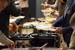 A group of people standing around a buffet line