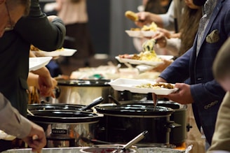 A group of people standing around a buffet line