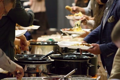 A group of people standing around a buffet line