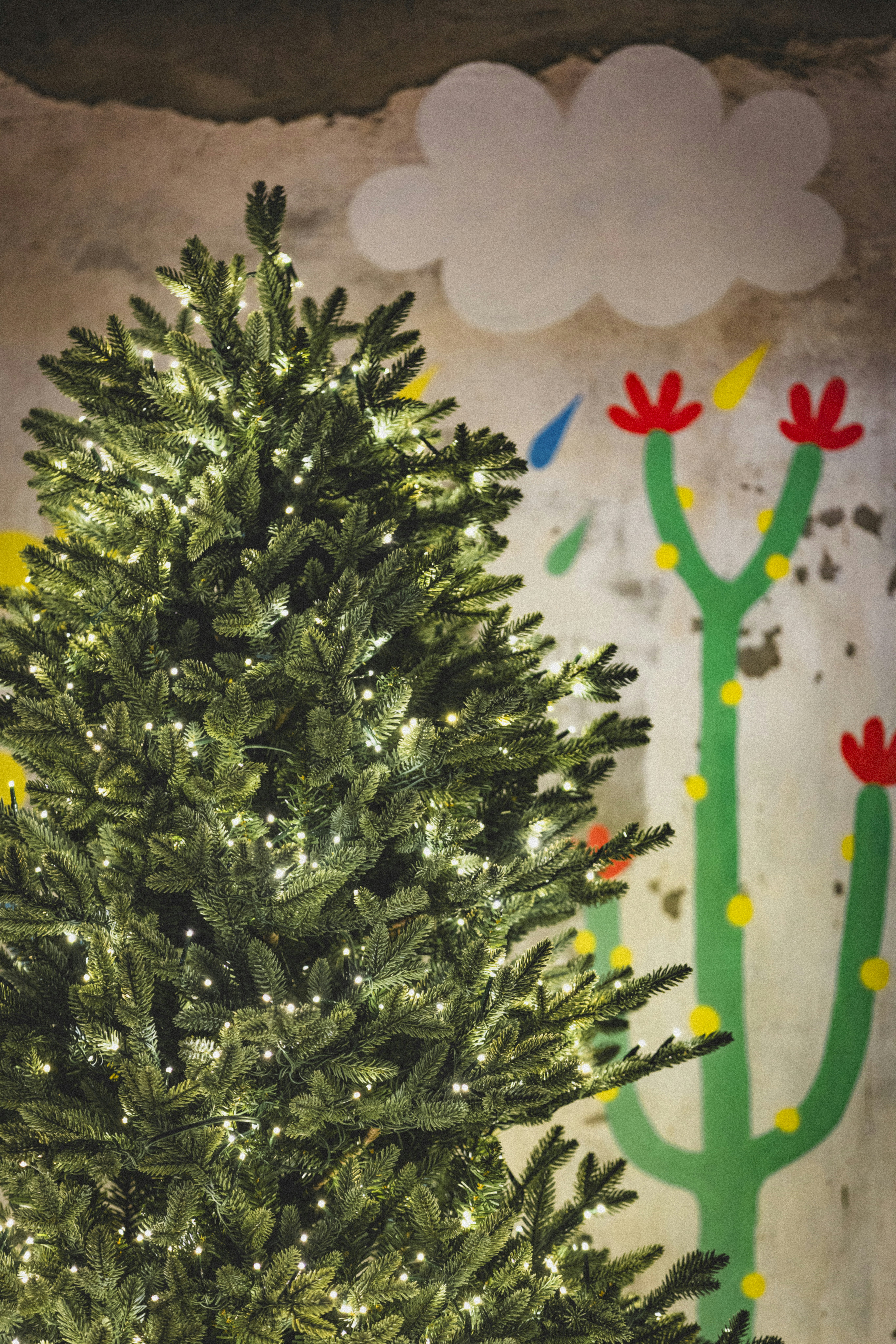 A christmas tree with a cactus painted on the wall behind it