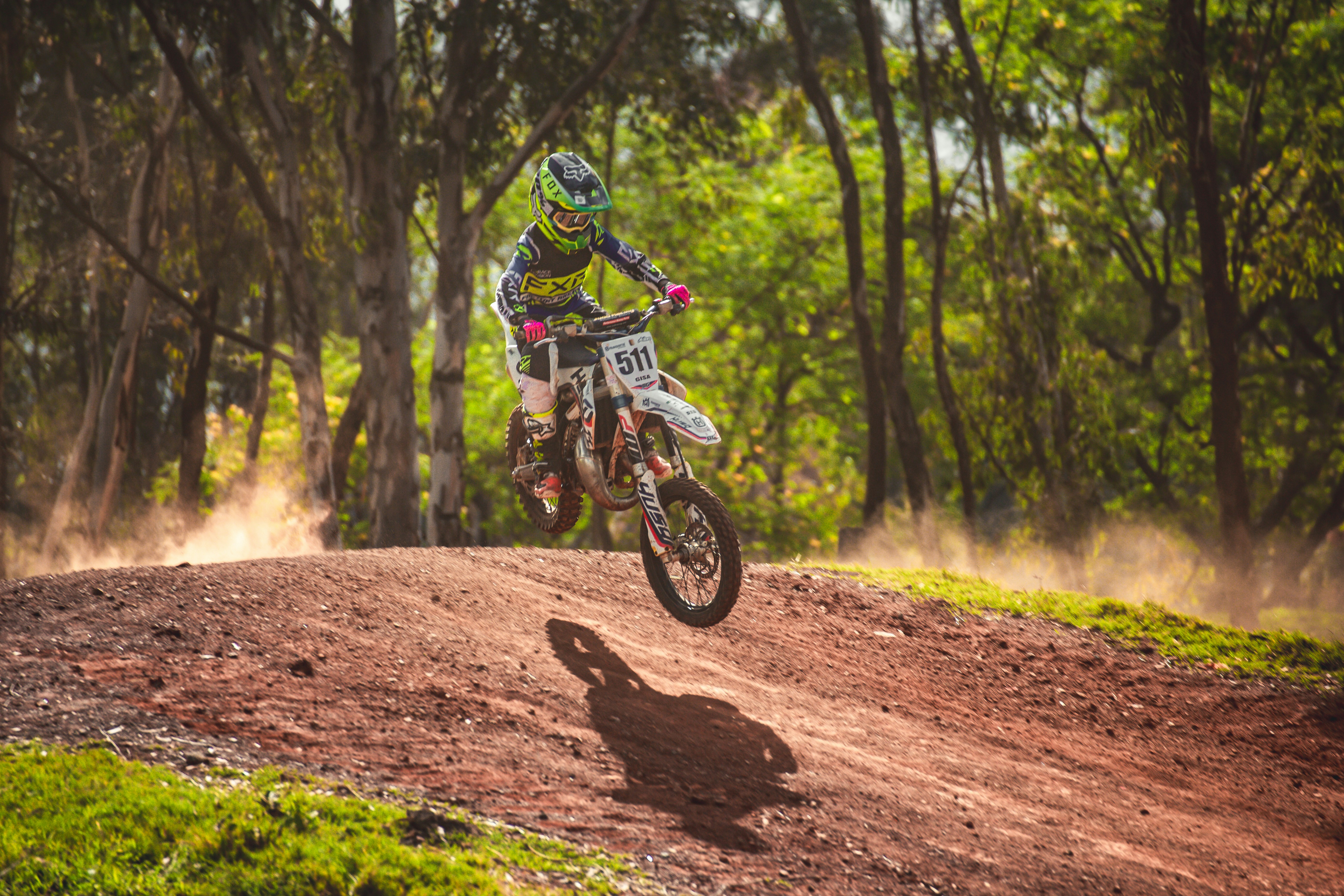 Honda CRF450R motocross bike jumping over dirt hill, extreme off-road action, dust clouds, competition