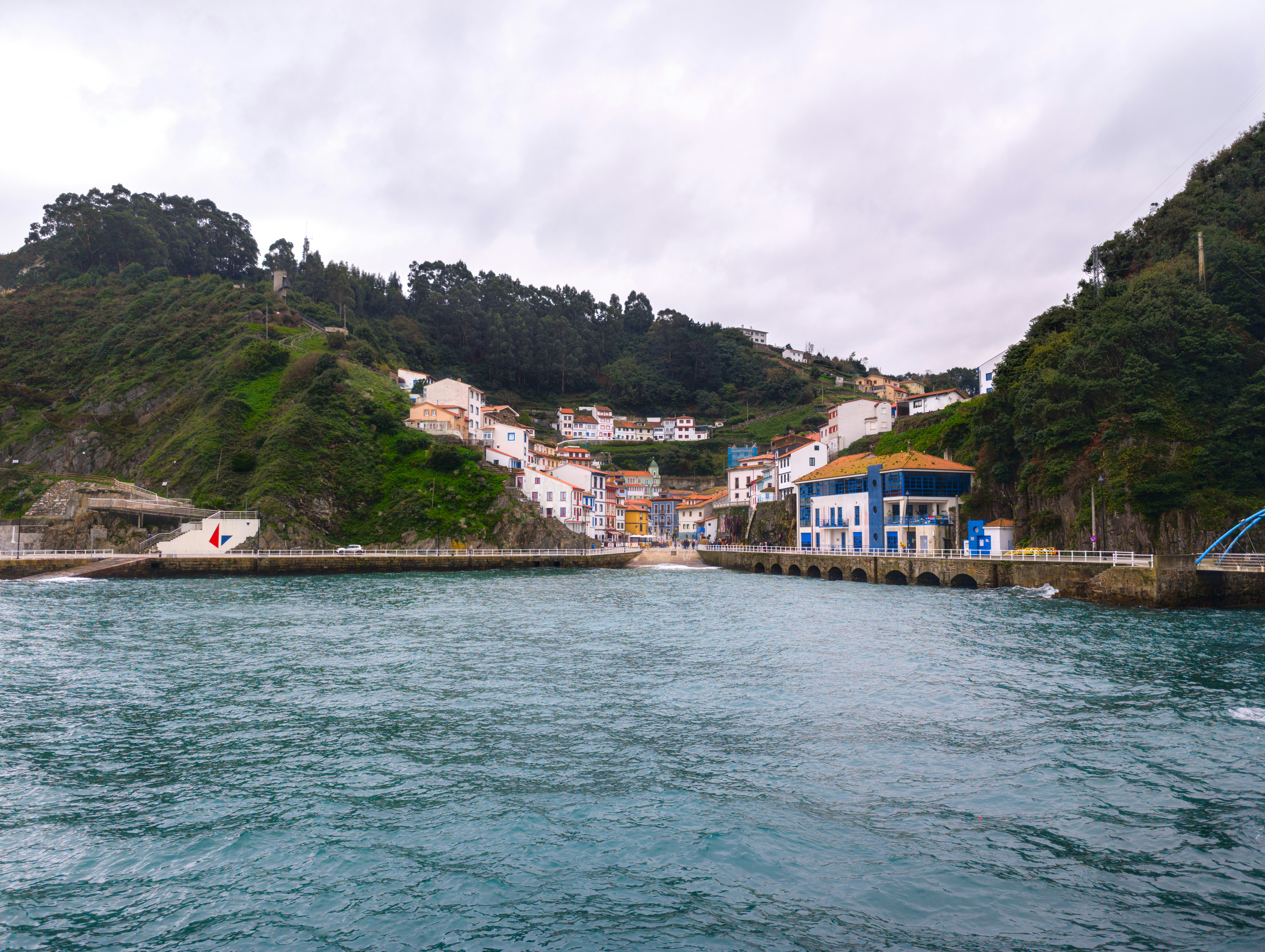 A body of water with houses on a hill in the background