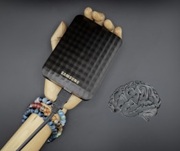 A hand holding a cell phone next to a brain