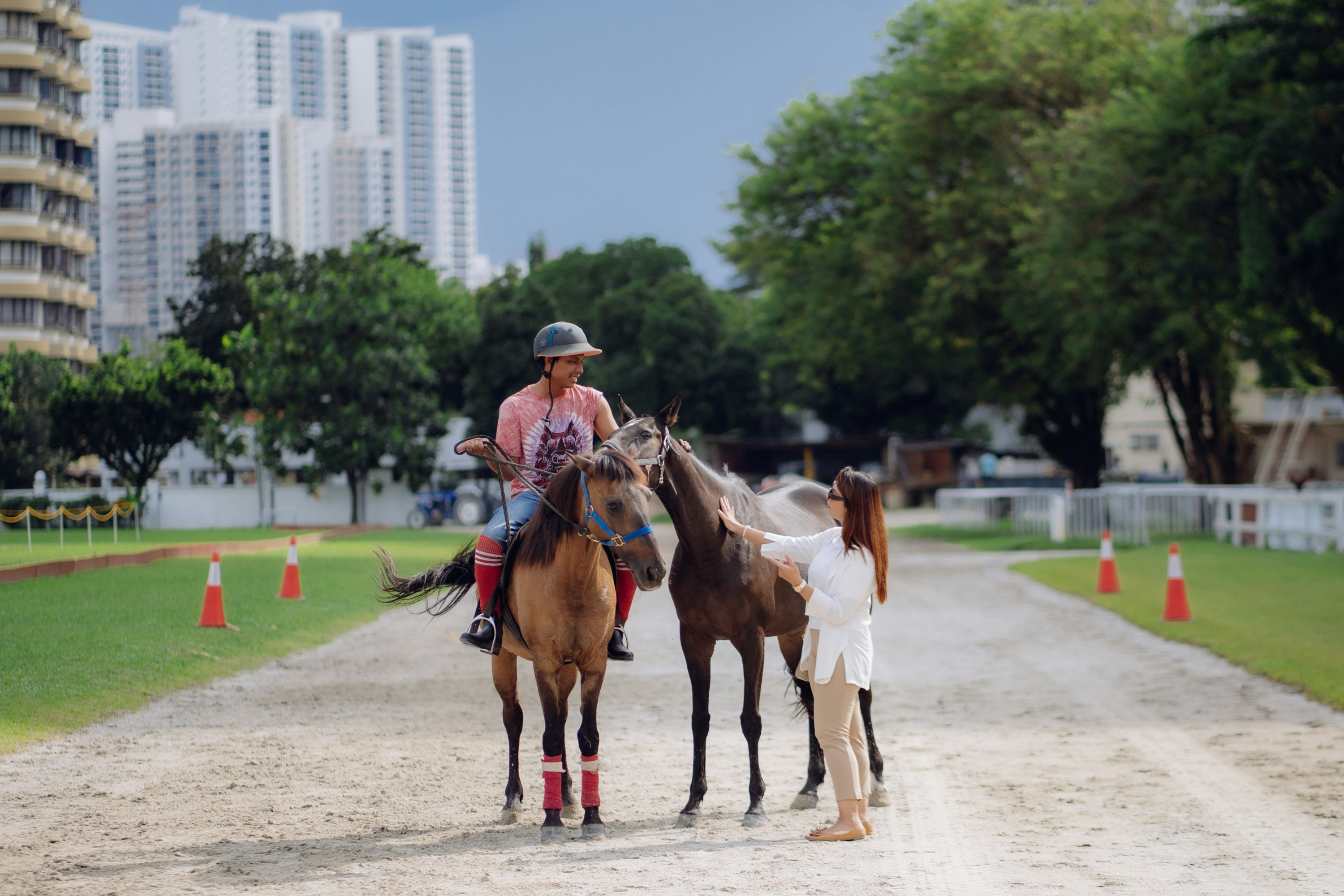 A man riding on the back of a brown horse down a dirt road