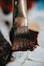 A close up of a paintbrush with brown paint on it
