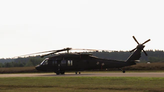 A black helicopter sitting on top of an airport runway