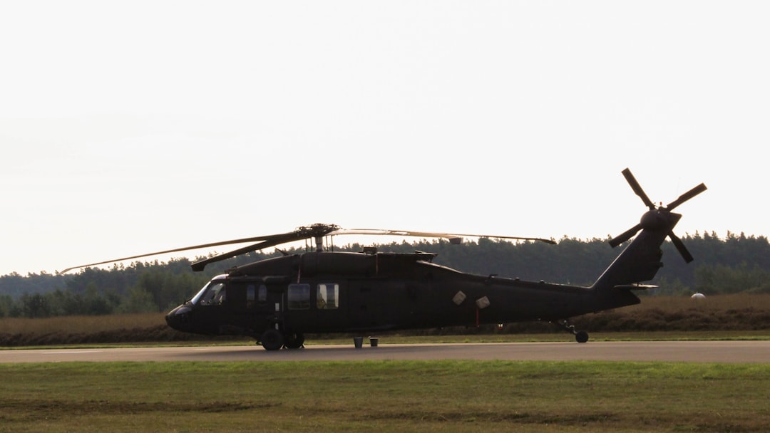 A black helicopter sitting on top of an airport runway, Swedish Air Force Blackhawk helicopter.