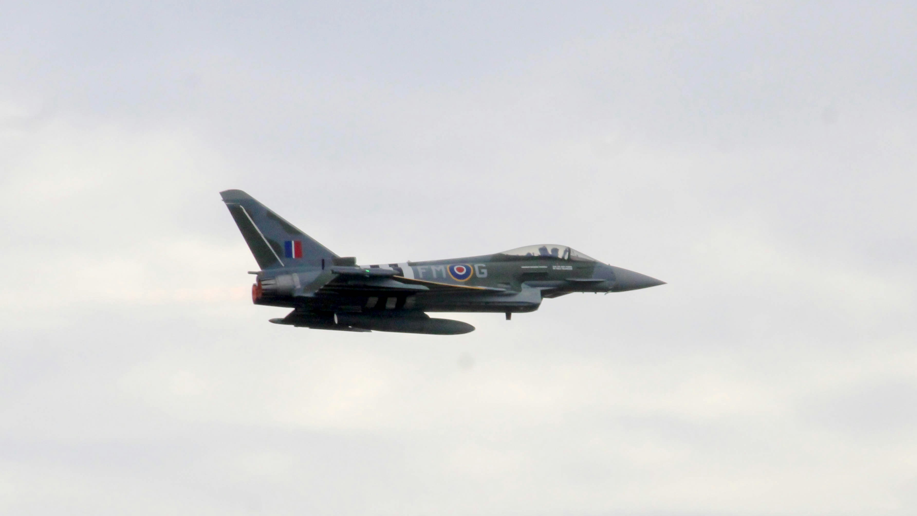 A fighter jet flying through a cloudy sky