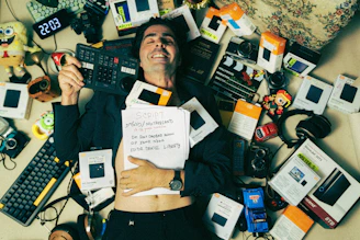 A man laying on top of a bed covered in electronics