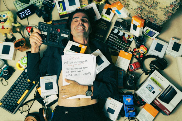 A man laying on top of a bed covered in electronics