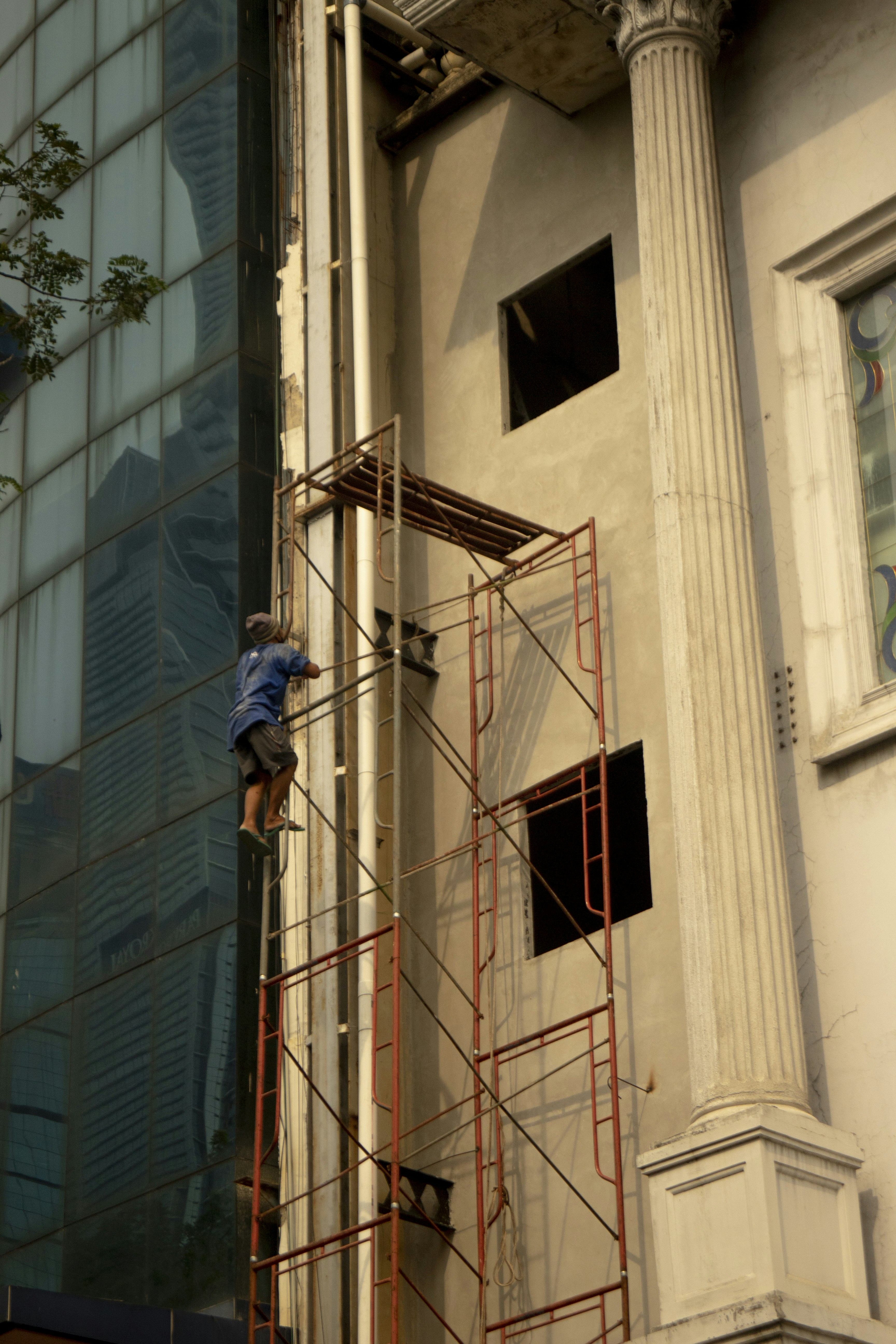 A man standing on a scaffolding next to a tall building