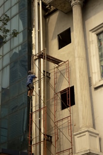 A man standing on a scaffolding next to a tall building