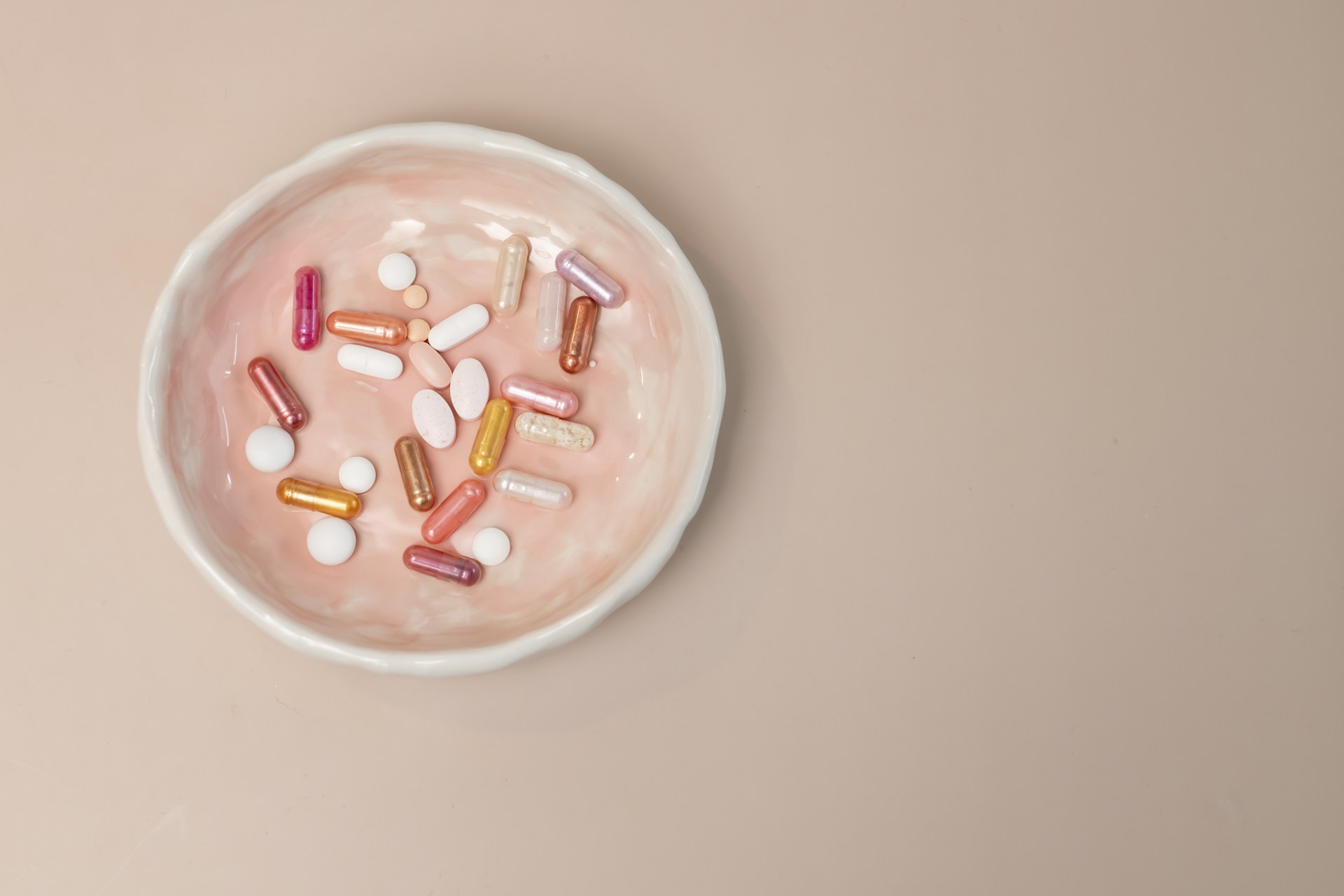 A white bowl filled with pills on top of a table