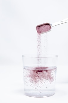 A spoon pouring red liquid into a glass