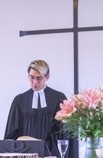 A man standing in front of a cross in a room