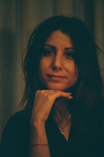 A woman sitting down with her hand on her chin