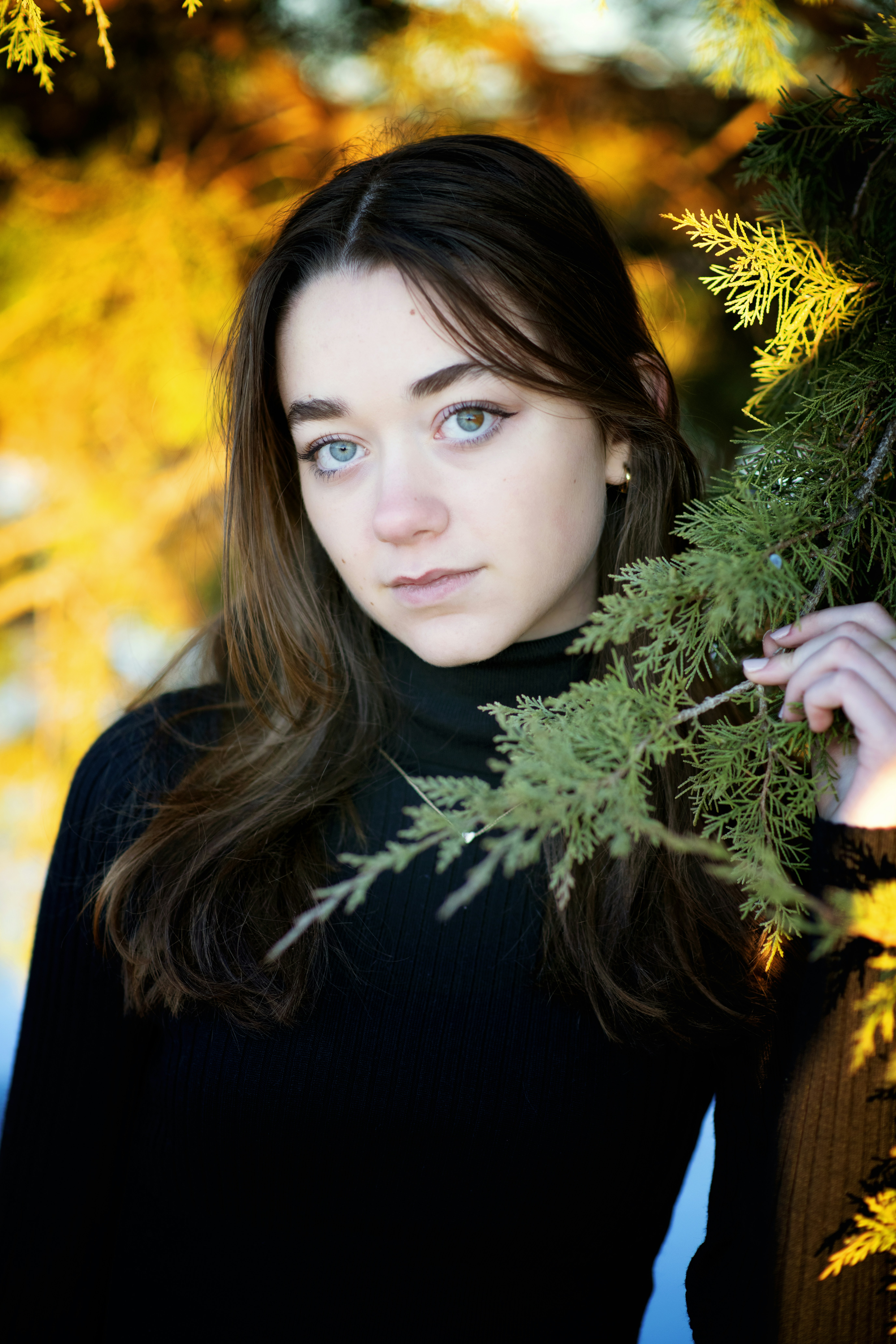 A beautiful young woman standing next to a tree