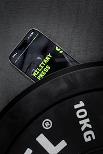 A cell phone sitting on top of a black clock