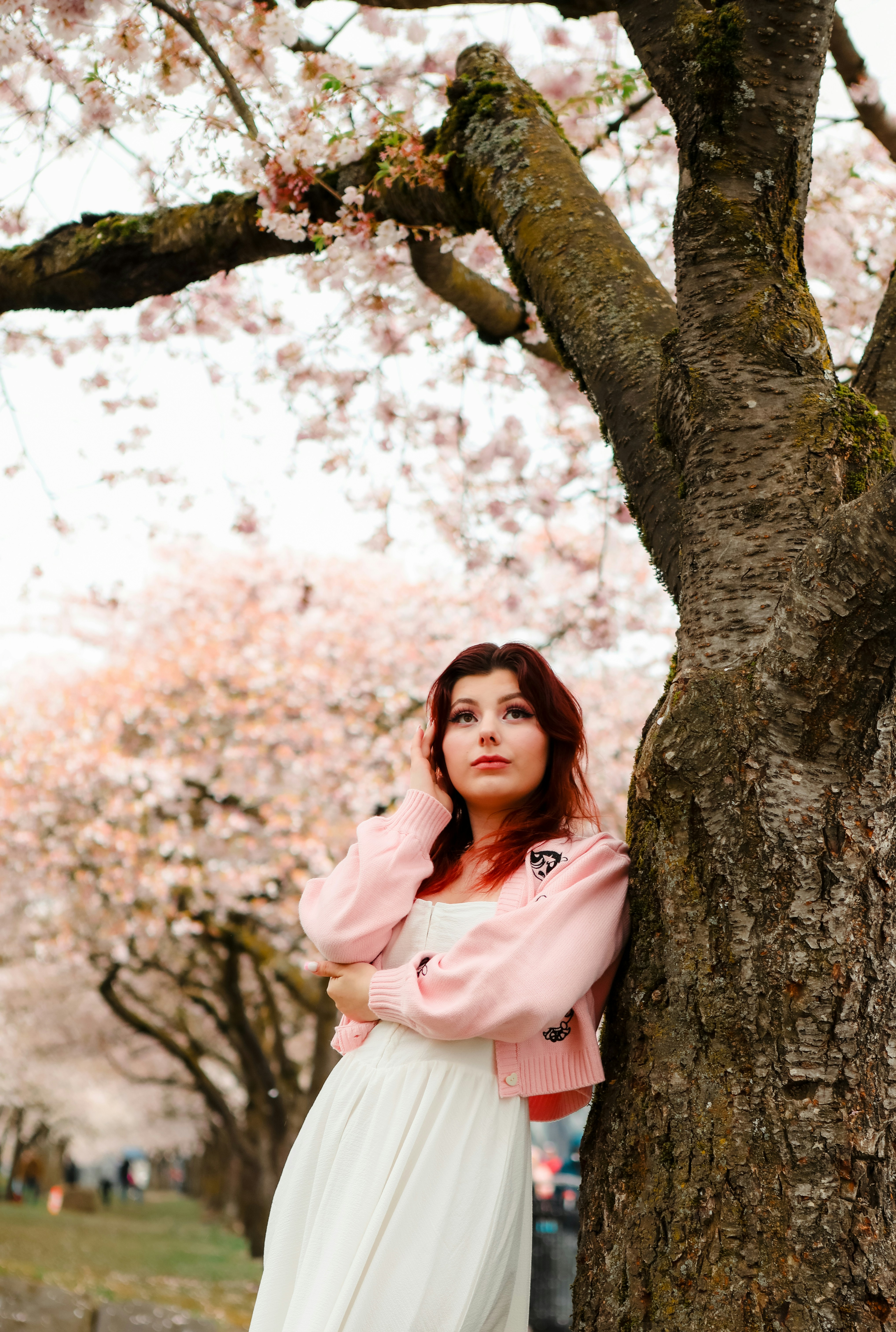 Une femme appuyée contre un arbre dans un parc