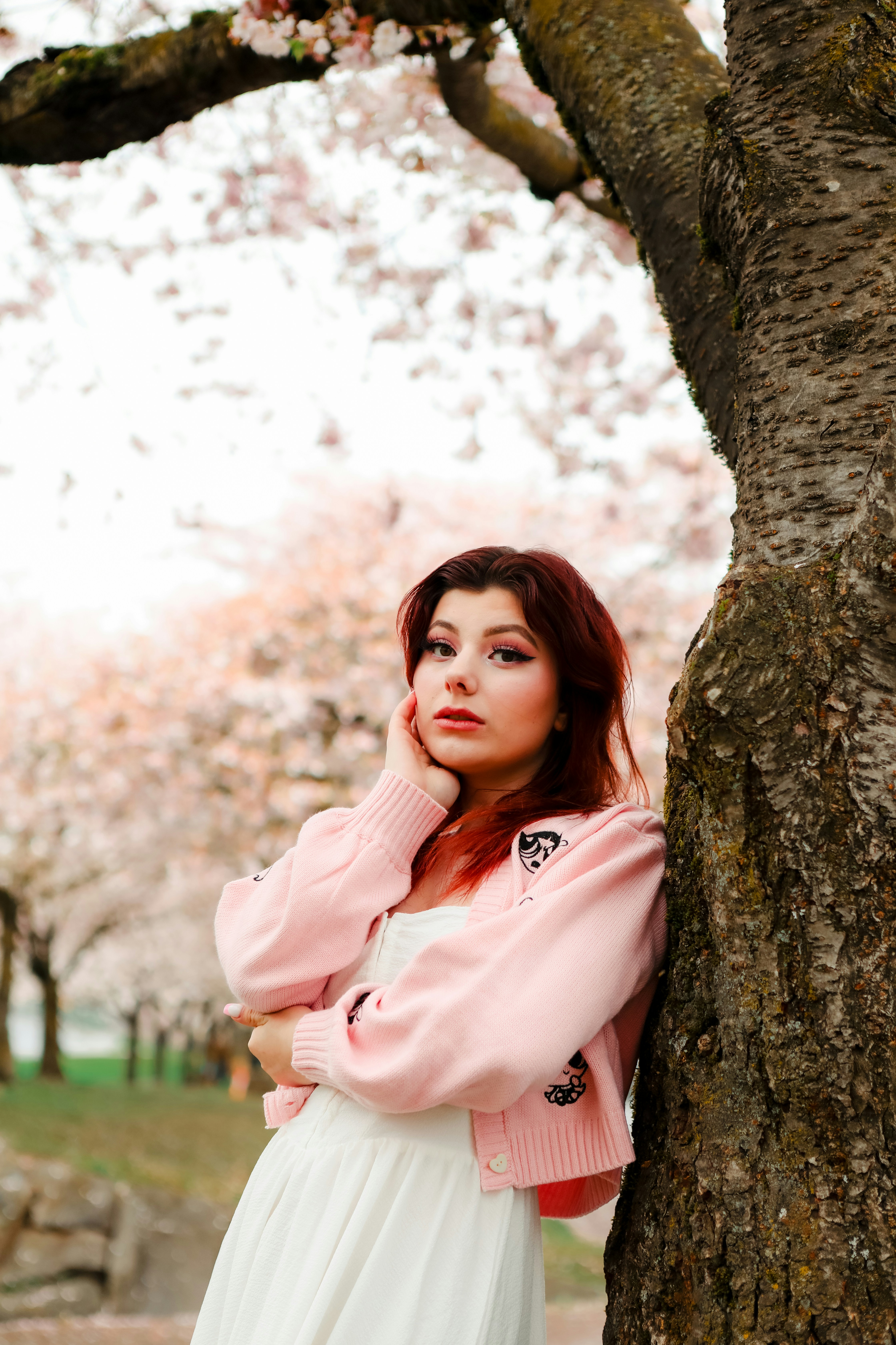 Une femme appuyée contre un arbre dans un parc