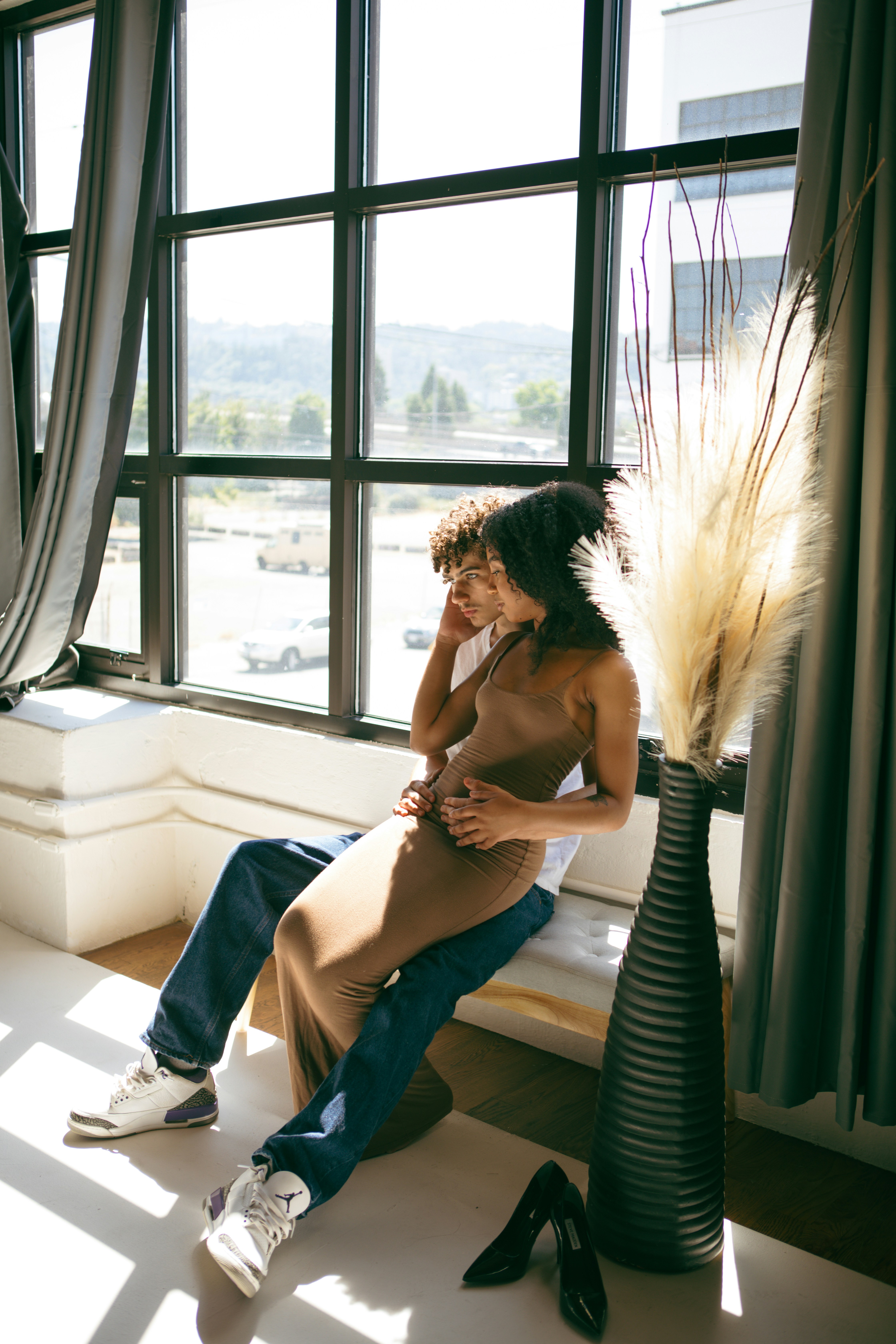 Une femme assise sur le rebord d’une fenêtre à côté d’un grand vase