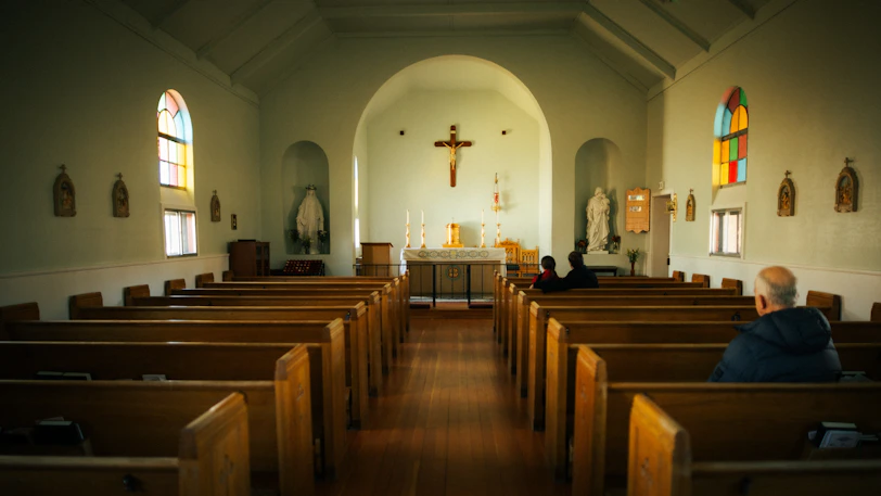 A man sitting in a church with stained glass windows