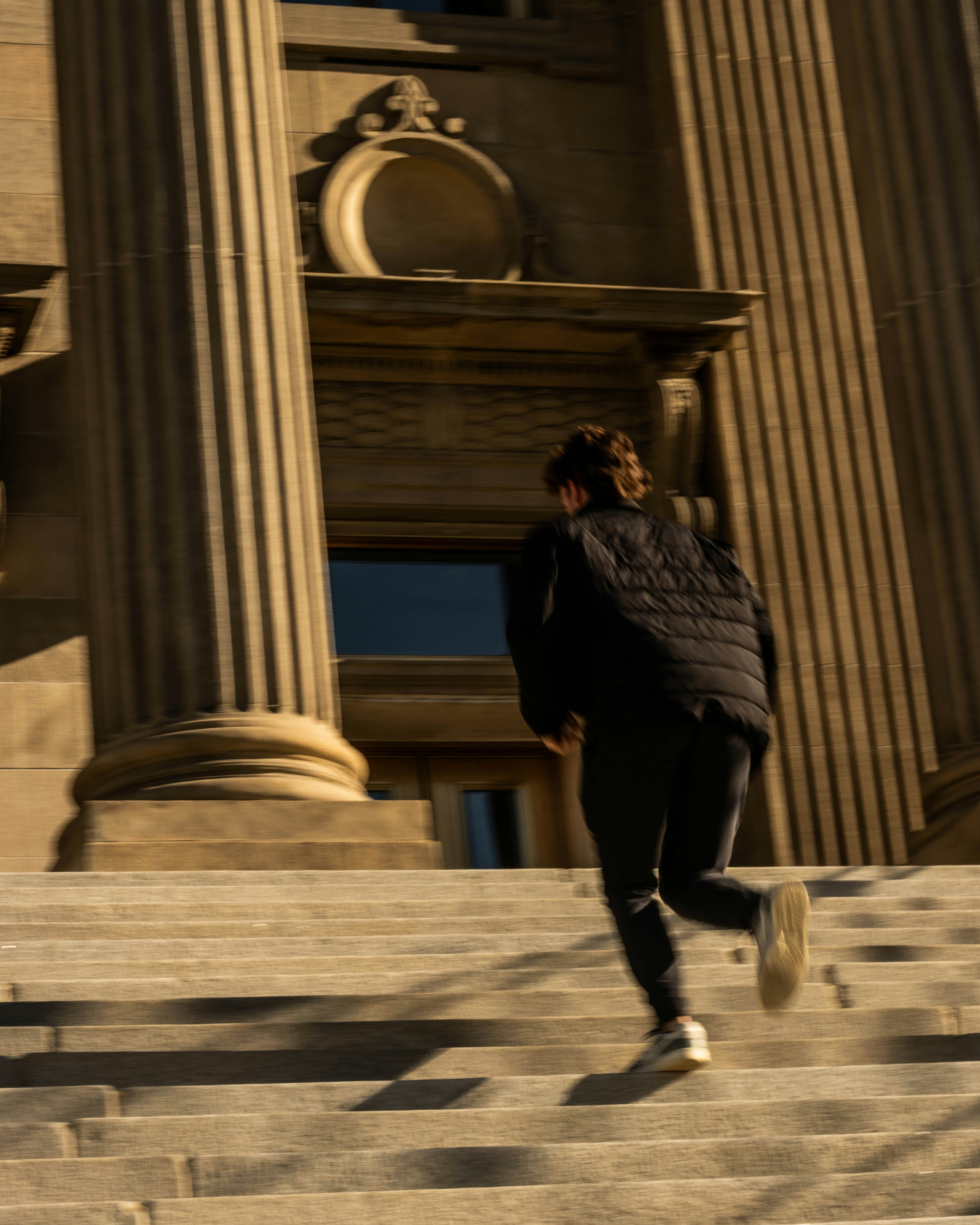 A man is running down some steps in front of a building