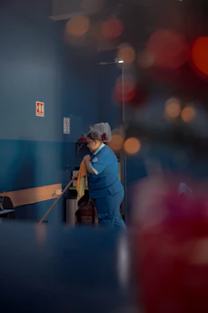 A woman in a blue uniform is cleaning a room