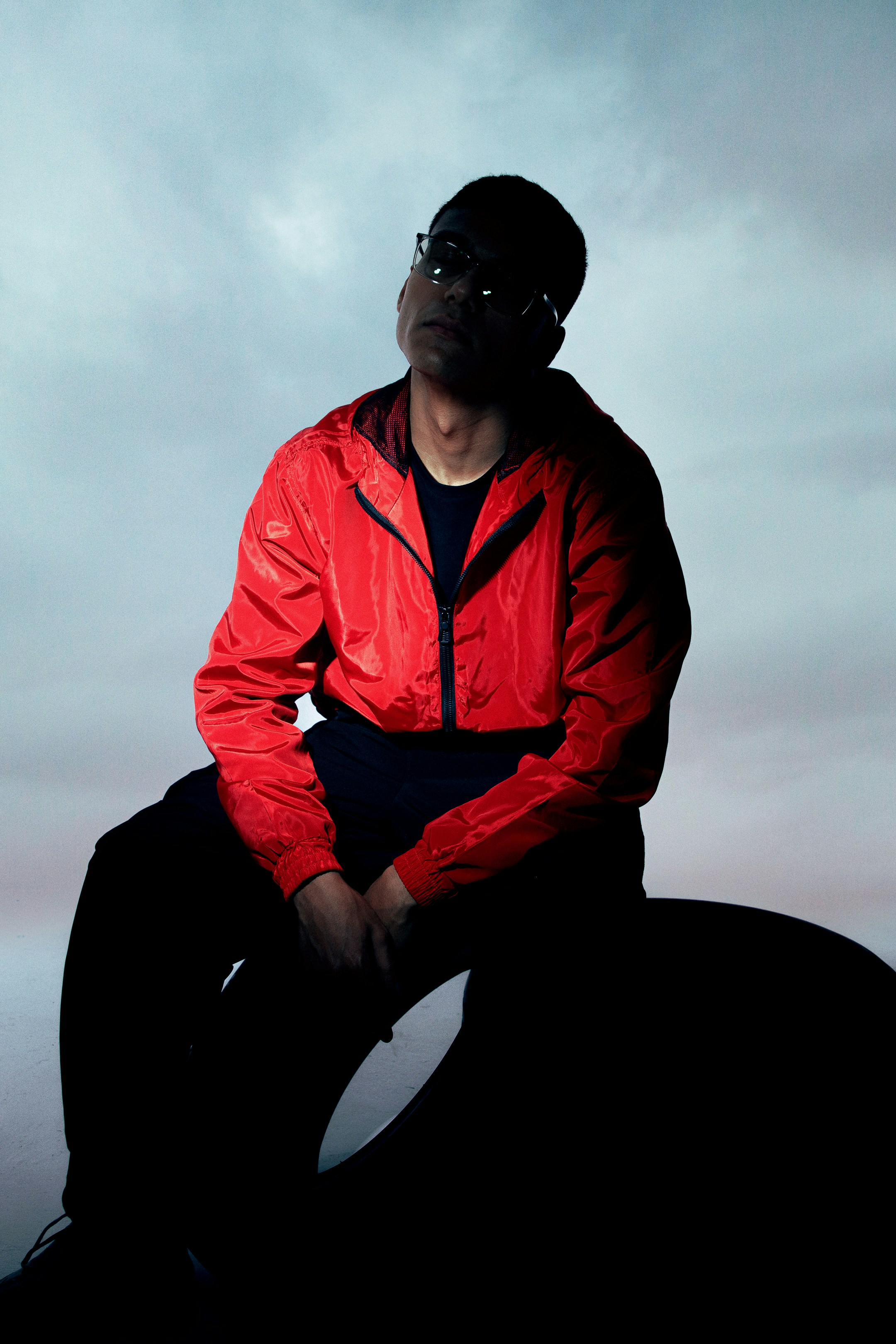 A man in a red jacket sitting on a rock