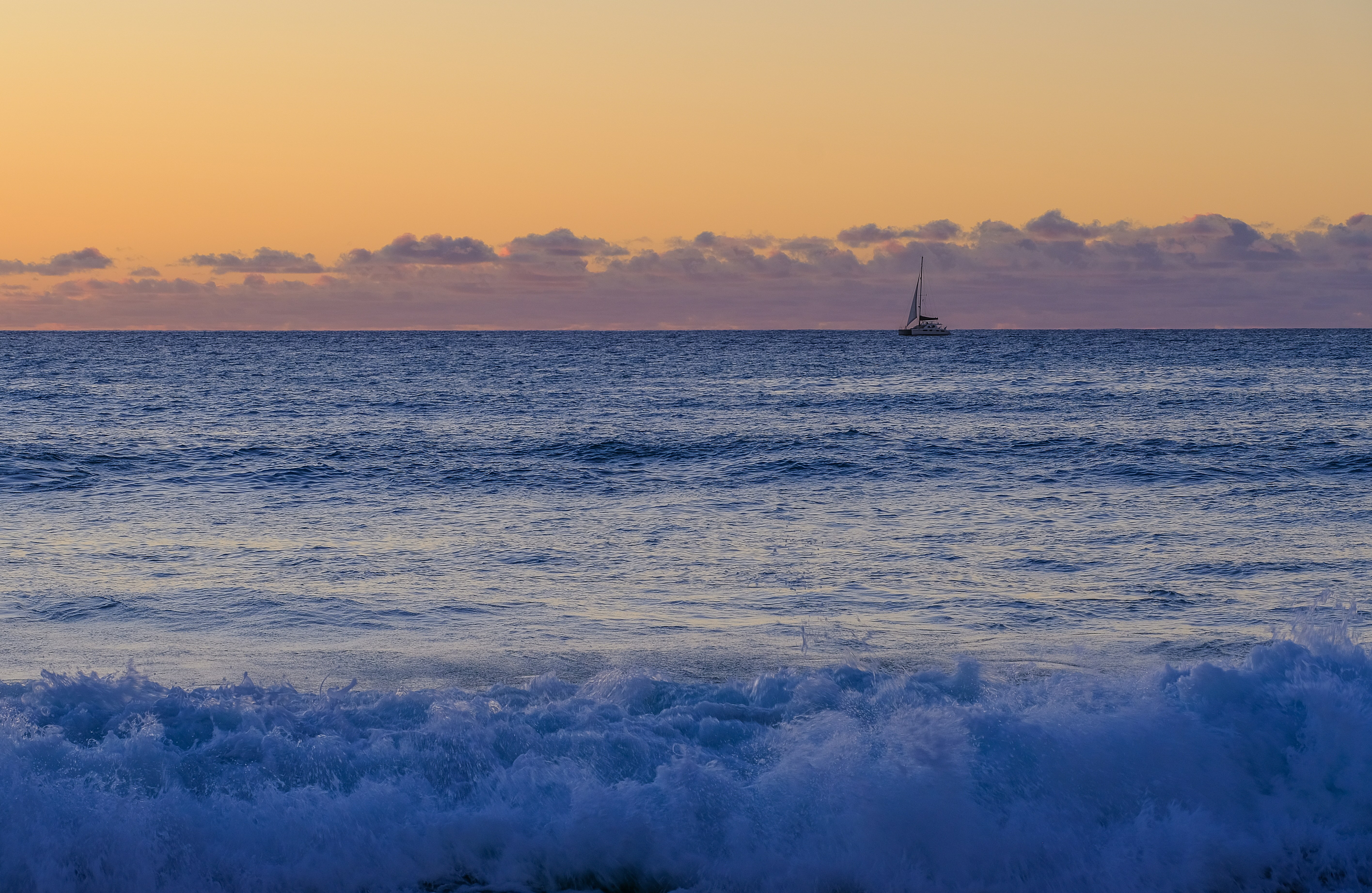 Um veleiro está no oceano ao pôr do sol