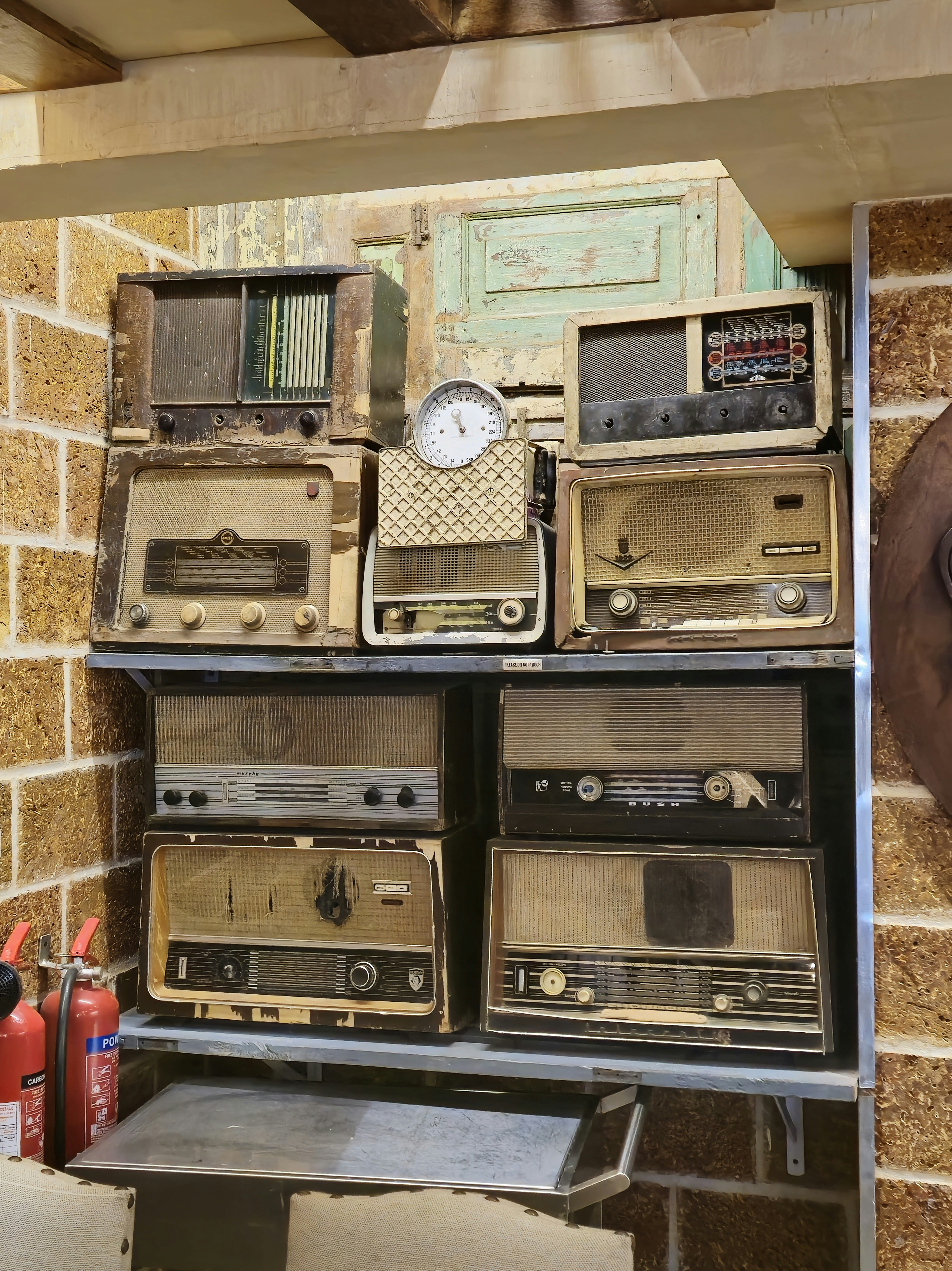 A bunch of old radio's are stacked on a shelf