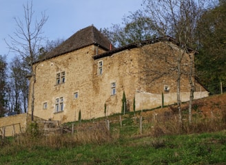 An old stone building on a hill with trees in the background