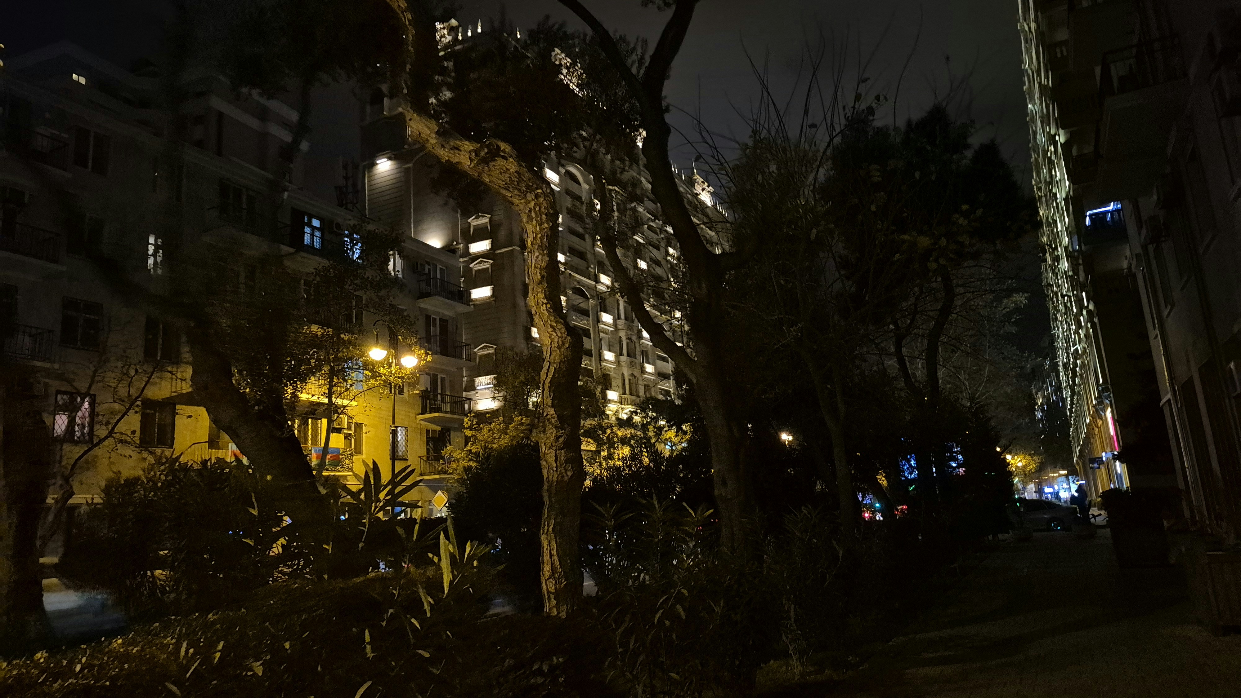 A city street at night with tall buildings