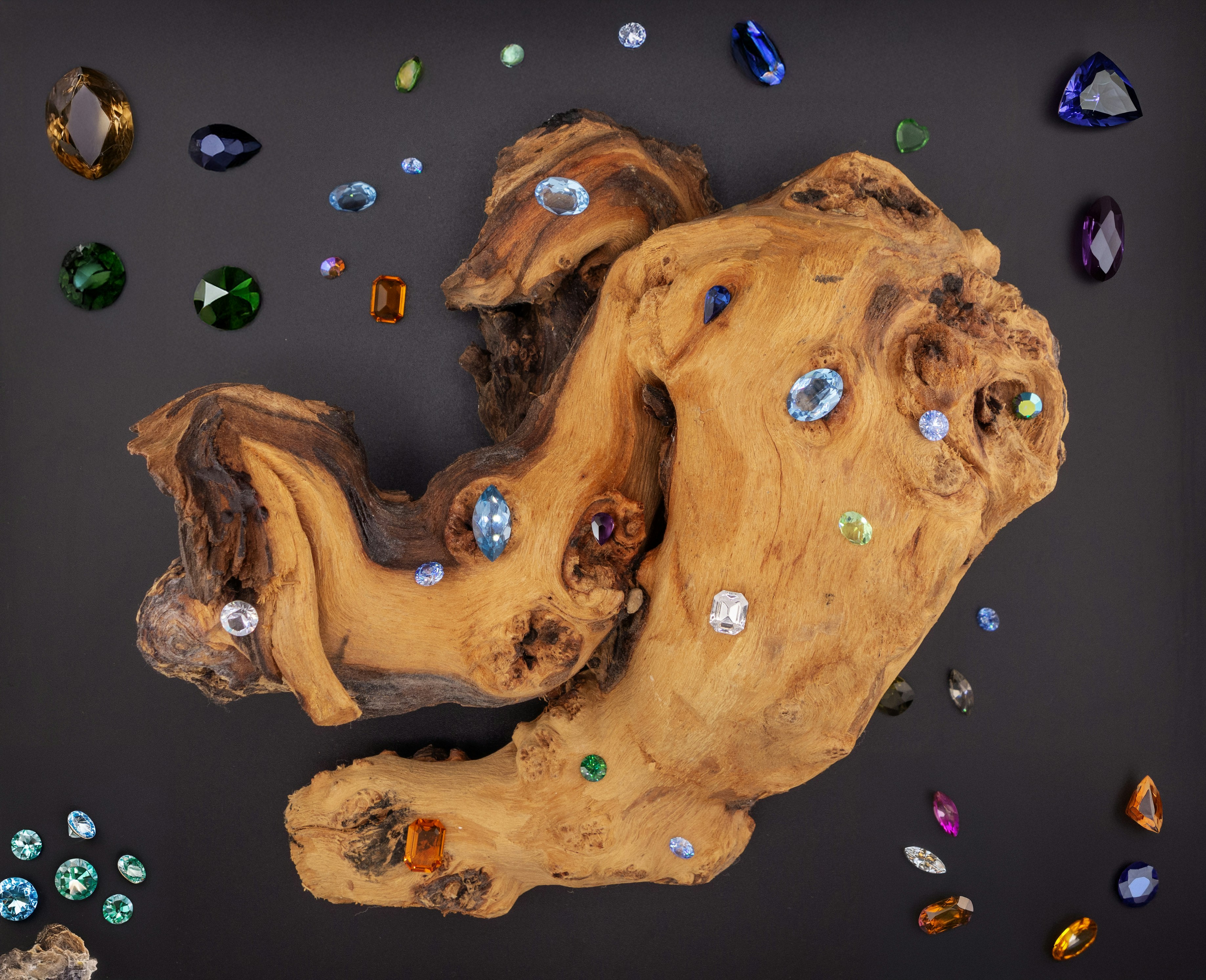 A piece of wood with many different colored stones on it