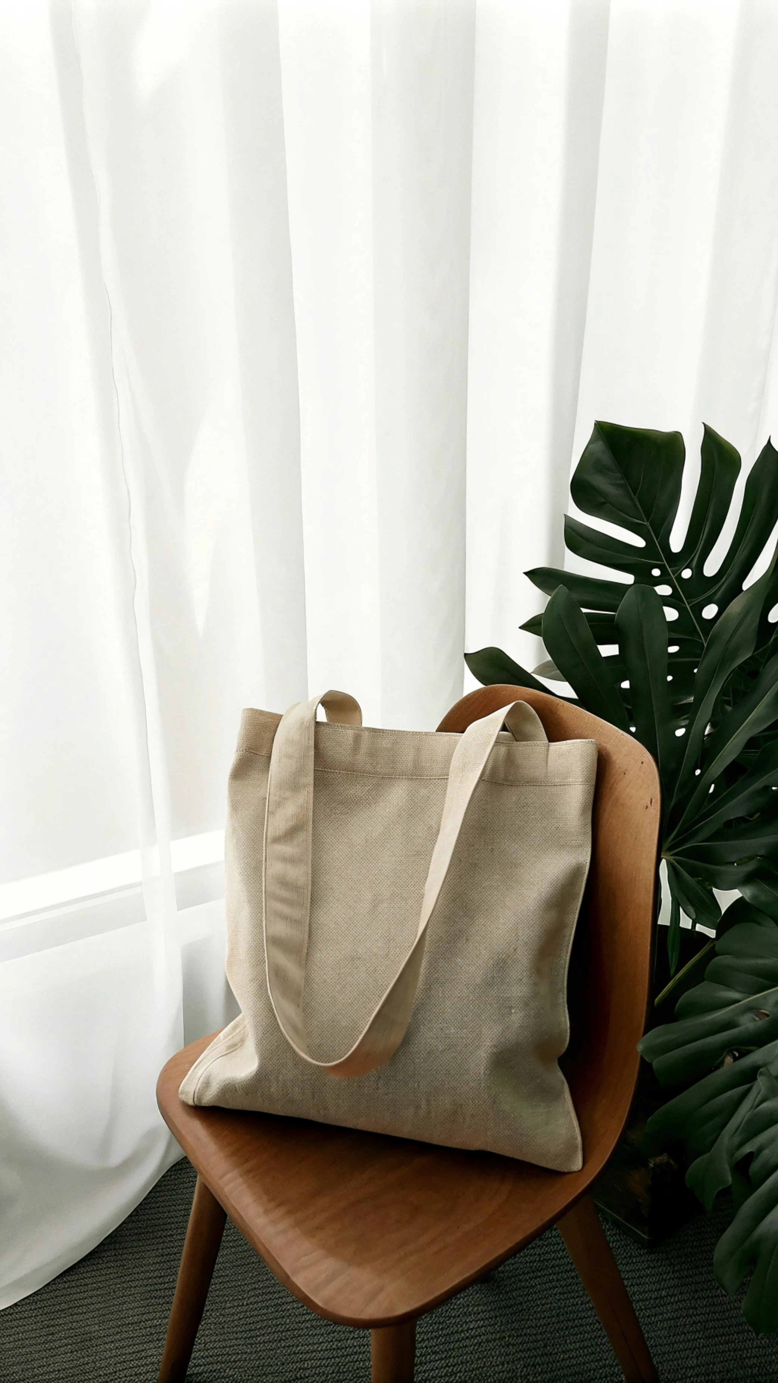 A bag sitting on top of a chair next to a plant