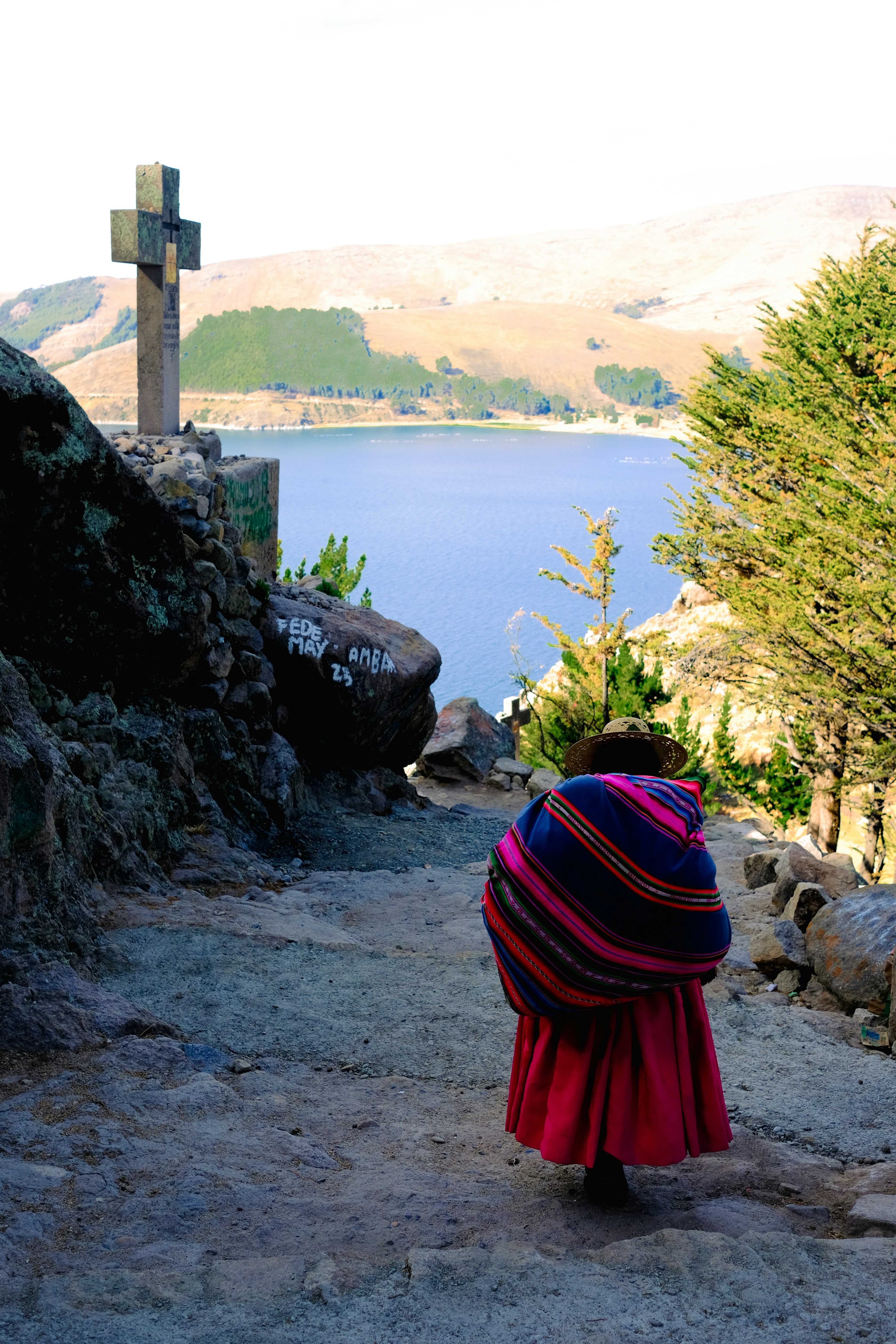 A woman walking up a hill towards a cross