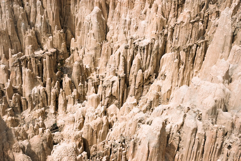 The image shows a large, light brown rock formation with numerous small holes and crevices scattered throughout its surface. The rocks vary in size and shape, creating a complex and visually interesting landscape. The perspective is from above, providing a bird's eye view of the formation that showcases the intricate details of the natural world.

The image does not contain any discernible text or human-made objects, making it appear to be a photograph taken by nature itself.