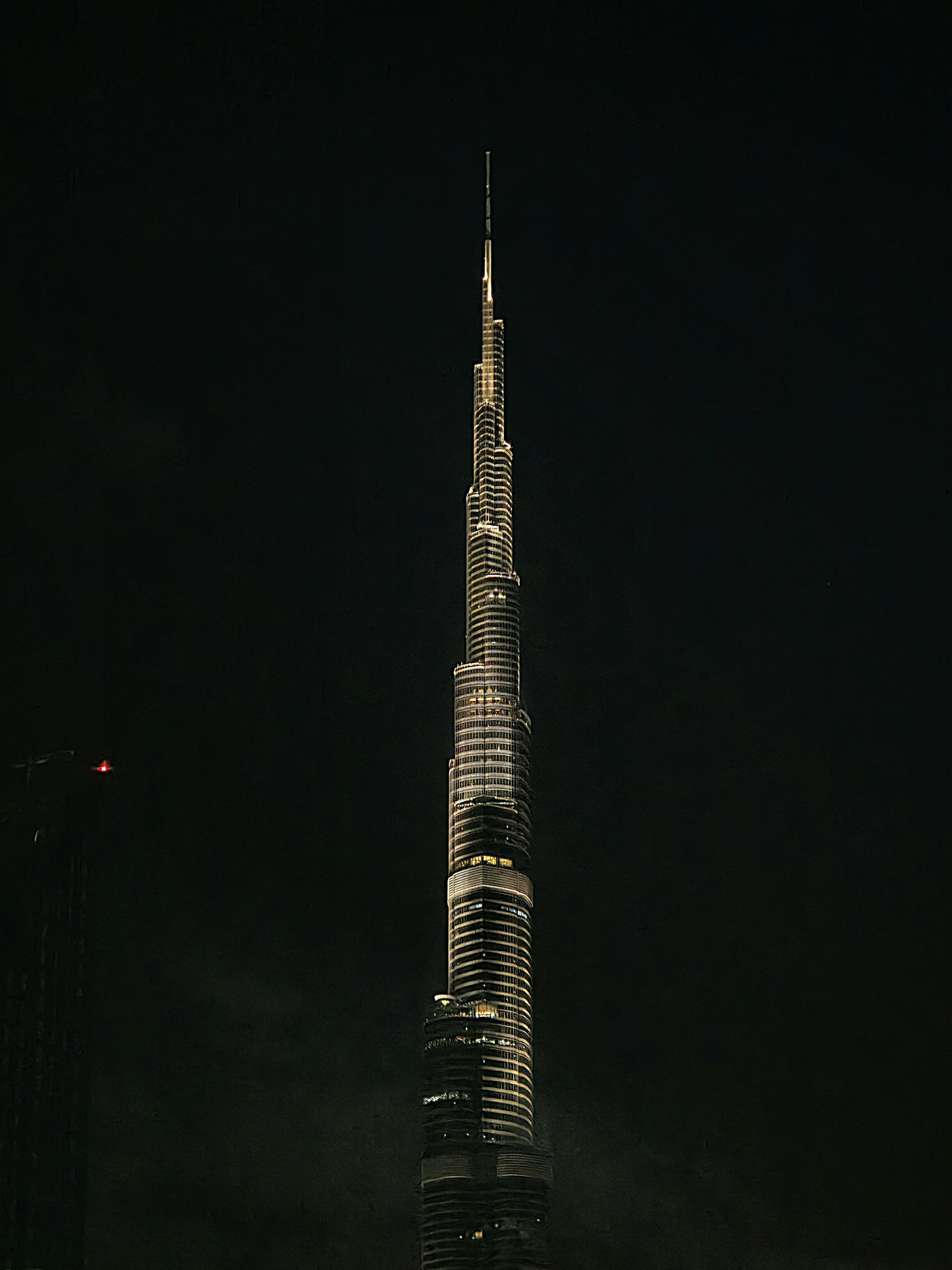 Downtown Dubai Burj Khalifa at dusk, bright golden hour, iconic tower against warm sky, city lights beginning to glow